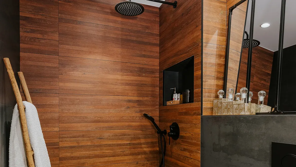 Baño con revestimiento de madera y ducha negra