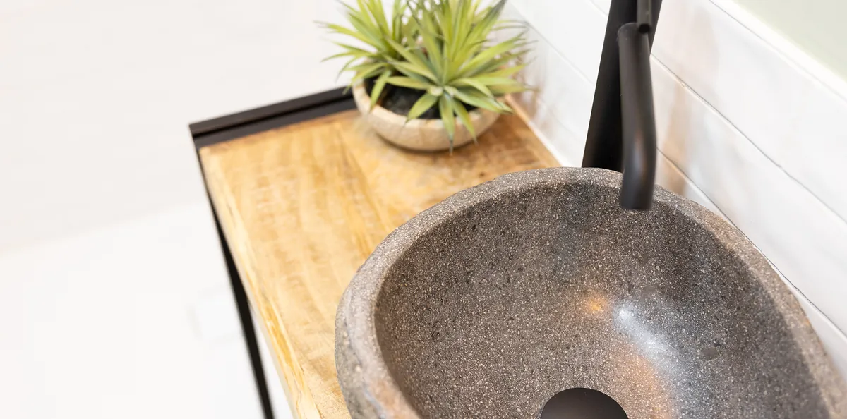 Detalle de lavabo de piedra sobre encimera de madera