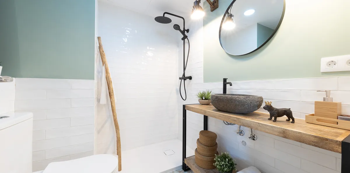 Baño con pared verde agua, lavabo de piedra y espejo redondo